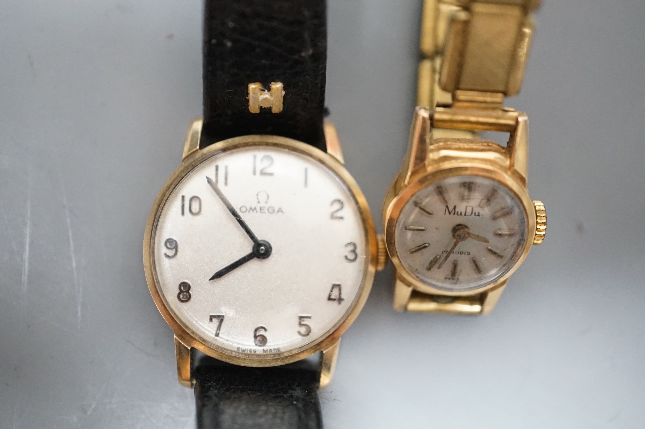 A lady's yellow metal Omega manual wind wrist watch, on a leather strap, with Omega box and a lady's 18k Mudu manual wind wrist watch on gilt metal strap.